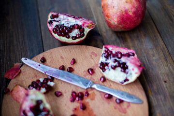 organic pomegranate open cut in half and full one on a wooden dark table background decorated in rustic style