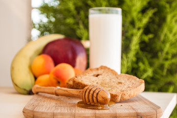 biscuits with honey and honey dipper with milk and fruits