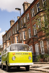 Plakat Old vintage green van parked in a street with victorian houses 