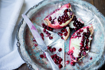 organic pomegranate open cut in half and full one on a wooden dark table background decorated in rustic style