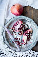 organic pomegranate open cut in half and full one on a wooden dark table background decorated in rustic style