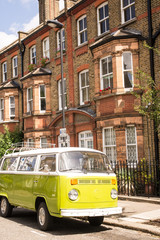 Old vintage green van parked in a street with victorian houses 