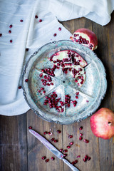 organic pomegranate open cut in half and full one on a wooden dark table background decorated in rustic style