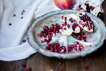 organic pomegranate open cut in half and full one on a wooden dark table background decorated in rustic style