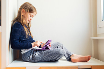 Adorable little girl playing on a digital tablet