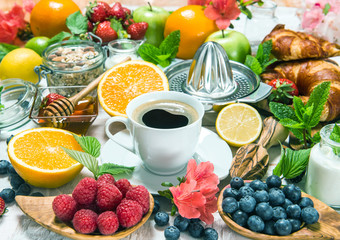 Coffee, croissants, granola, honey, fresh berries, fruits orange