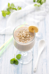 Healthy banana smoothies with oatmeal in a glass on a blue background