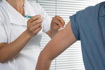 A man is getting an injection with a syringe at hospital