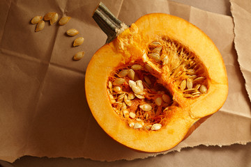 Half of a fresh Pumpkin split open with seeds on torn paper background. 