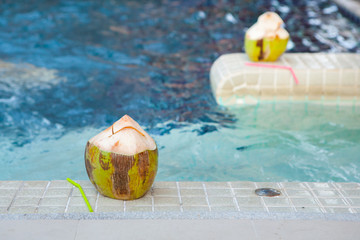 Coconut with straws to drink on the side of the pool
