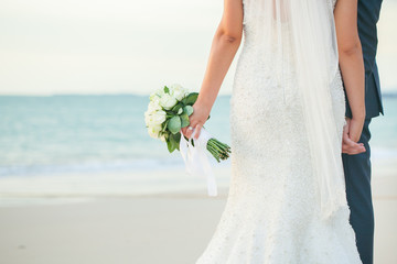 A beautiful bride with white roses in the hand.