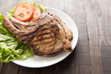 Grilled steak with vegetables on a wooden background.
