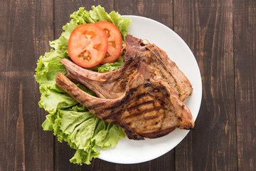 Grilled steak with vegetables on a wooden background.