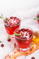 Cranberry cocktail with rosemary garnish, honey and soda on wooden background. Selective focus