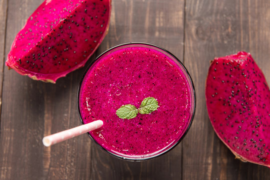 Red dragon fruit smoothie on wooden background.