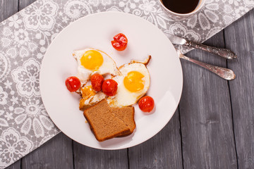 Fried eggs with cherry tomatoes and mug of black coffee. Breakfast concept. Selective focus