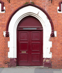 Crimson door on brick wall background.