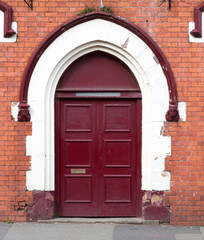 Fototapeta premium Crimson door on brick wall background.