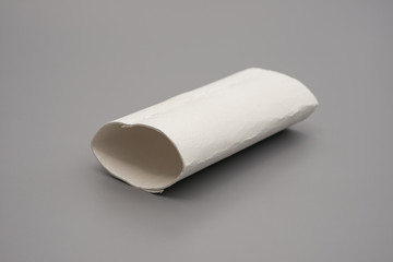 smashed toilet roll with the last bit of tissue on grey
