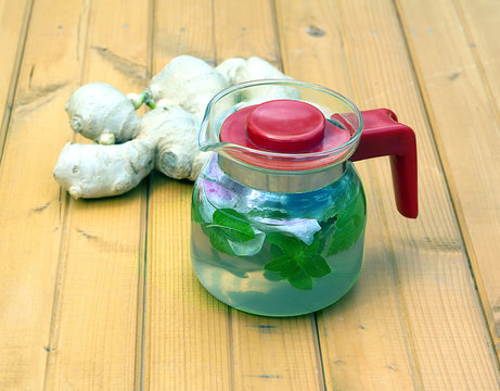 Spa tea with briar, mint and ginder in glass kettle on brown table