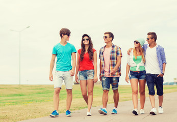 Obraz premium group of smiling teenagers walking outdoors