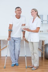 Man with crutch speaking with his doctor 