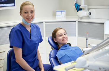 happy female dentist with patient girl at clinic
