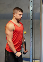 man flexing muscles on cable machine gym