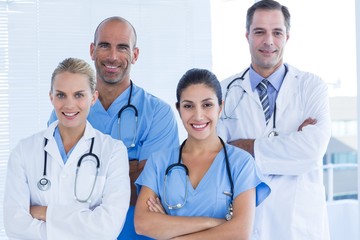 Team of smiling doctors looking at camera with arms crossed