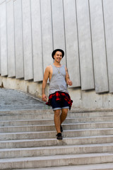 cool young and handsome caucasian brunette hipster skater guy wearing a hat posing smiling and having fun outside during amazing summer day in the city with