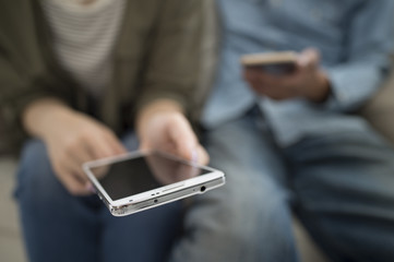 The couple are looking at a smart phone sitting on the sofa