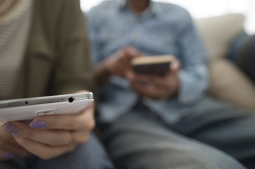 Men and women are looking at smart phone sitting on the sofa