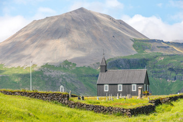 Icelandic wooden church next to mountains.