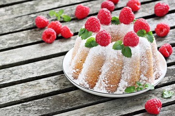 Vanilla bundt cake with raspberries on a rustic dark background 