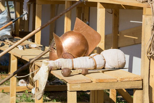 gladiator helmet, sword and spear on wooden bench