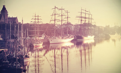 Retro toned photo of sailing ships at sunrise, Szczecin, Poland. - obrazy, fototapety, plakaty