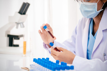 close up of scientist holding and examining blood sample in lab