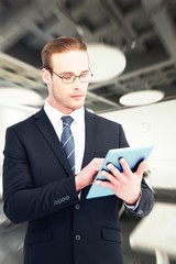 Composite image of unsmiling businessman using tablet pc