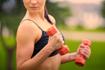 Female fitness instructor exercising with small weights in green