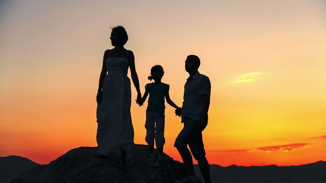 Silhouette of family on the beach at sunset. Mom shows the trend