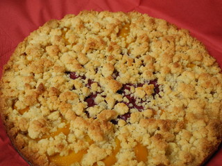 Kirsch-Pfirsich-Butterstreusel-Kuchens mit rotem Hintergrund