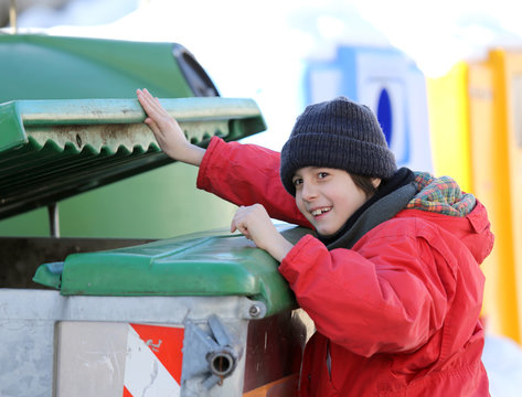 poor young boy tries to eat into the waste box in winter
