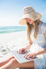Fototapeta premium Woman using laptop and wearing hat