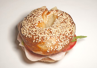 Big bagel sandwich with tomato cheese and ham on white background