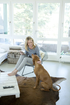 Woman with her dog and digital tablet at home