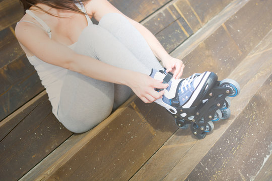 young woman with roller-skates sitting on a staircase