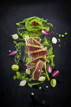 Food art, slices of raw tuna with herbs and wasabi pea paste