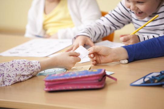 Pupils handing over slip of paper in classroom
