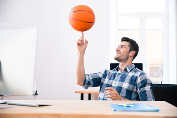 Happy businessman spining ball in office