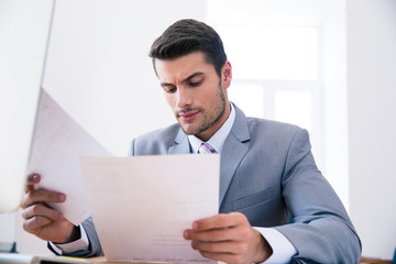 Confident businessman reading documents in office